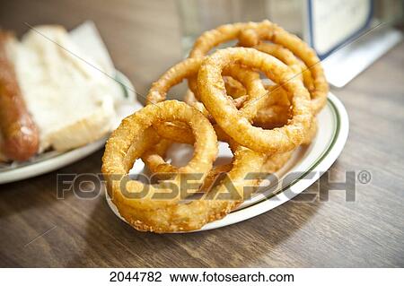 Stock Image - Plate Of Onion Rings And Hot Dog On Wooden Countertop. Fotosearch