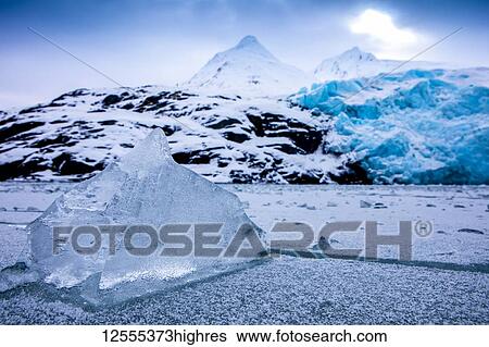 Stock Photograph - Portage Lake frozen in winter with Portage Glacier in the background, frozen ice in foreground; Alaska, United States of America. Fotosearch