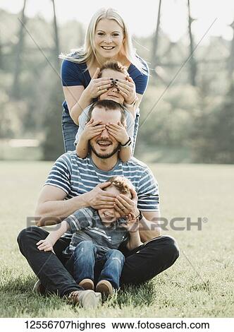 Portrait of a family with young children in a park, standing in a row covering each other's eyes; Edmonton, Alberta, Canada View Large Photo Image Stock Photograph - Portrait of a family with young children in a park, standing in a row covering each other's eyes; Edmonton, Alberta, Canada. Fotosearch