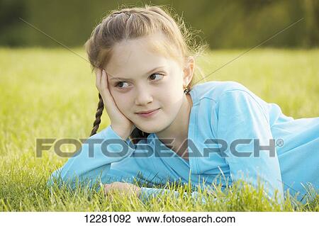 Stock Image - Portrait of girl laying down in grass; Toronto, Ontario, Canada. Fotosearch
