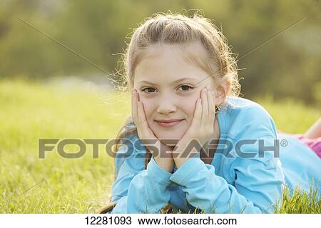 Stock Image - Portrait of girl laying down in grass; Toronto, Ontario, Canada. Fotosearch