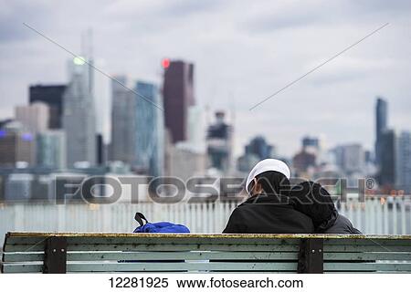 Romantic couple is resting on a bench with skyscrapers in the background; Toronto, Canada View Large Photo Image Stock Photography - Romantic couple is resting on a bench with skyscrapers in the background; Toronto, Canada. Fotosearch