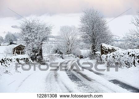 Stock Photo - Rural road covered in snow, making it hard to travel; Wensleydale, North Yorks, England. Fotosearch