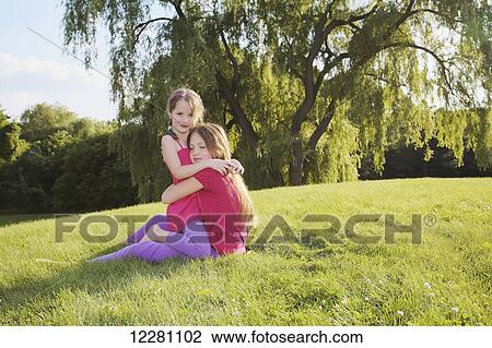 Stock Image - Sisters playing in a park; Toronto, Ontario, Canada. Fotosearch