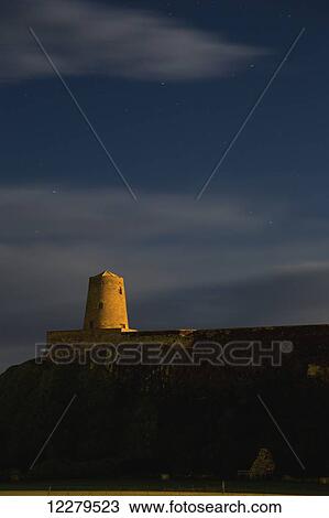 Stock Image - Sunlight shining on a tower of Bamburgh Castle; Bamburgh, Northumberland, England. Fotosearch