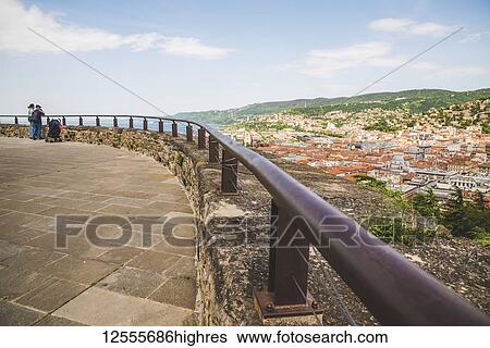 Tourists stand looking out over the coastline and Duino from Duino Castle; Italy View Large Photo Image Stock Photograph - Tourists stand looking out over the coastline and Duino from Duino Castle; Italy. Fotosearch