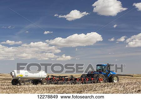 Tractor and air seeder with nitrogen tank in stubble field planting crop with blue sky and clouds; Alberta, Canada View Large Photo Image Stock Photo - Tractor and air seeder with nitrogen tank in stubble field planting crop with blue sky and clouds; Alberta, Canada. Fotosearch