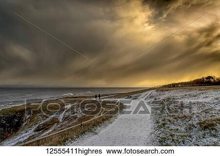 Two figures walking on the snowy path along the coast at dusk; South Shields, Tyne and Wear, England View Large Photo Image Stock Photograph - Two figures walking on the snowy path along the coast at dusk; South Shields, Tyne and Wear, England. Fotosearch