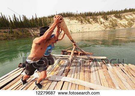 Stock Photo - Two people steering a handmade raft down the Yukon River near Carmacks, Yukon Territory, Canada. Fotosearch