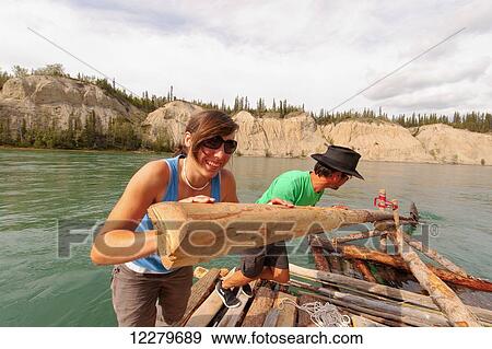 Stock Photo - Two people steering a handmade raft down the Yukon River near Carmacks, Yukon Territory, Canada. Fotosearch