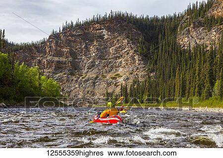 Stock Photograph - Two women packrafters negotiating a tributary of the Charley River in summertime, YukonCharley Rivers National Preserve; Alaska, United States of America. Fotosearch