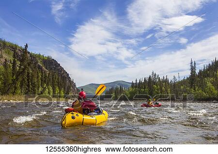 Stock Photograph - Two women packrafters negotiating a tributary of the Charley River in summertime, YukonCharley Rivers National Preserve; Alaska, United States of America. Fotosearch