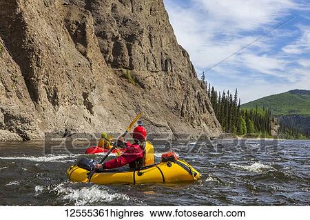 Stock Photograph - Two women packrafters negotiating a tributary of the Charley River in summertime, YukonCharley Rivers National Preserve; Alaska, United States of America. Fotosearch