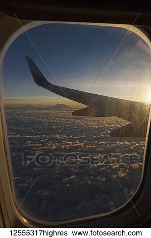Stock Photograph - View of Denali and Alaska Range from Alaska Airlines jet at sunset with clouds; Alaska, United States of America. Fotosearch