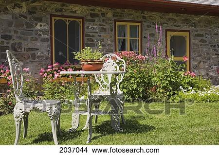 White Cast Iron Garden Chairs And Table On The Front Lawn Of An