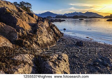 Stock Photograph - Winter sunset on rocky beach looking out over Crescent Bay; Sitka, Alaska, United States of America. Fotosearch