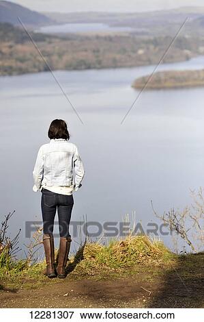 Stock Photo - Woman admiring view over Derwentwater and towards Bassenthwaite Lake in the English Lake District; Cumbria, England. Fotosearch