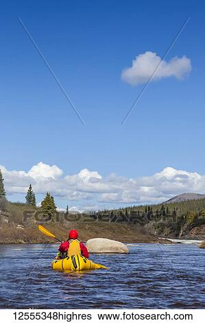 Stock Photograph - Woman packrafting and negotiating a tributary of the Charley River in summertime, YukonCharley Rivers National Preserve; Alaska, United States of America. Fotosearch