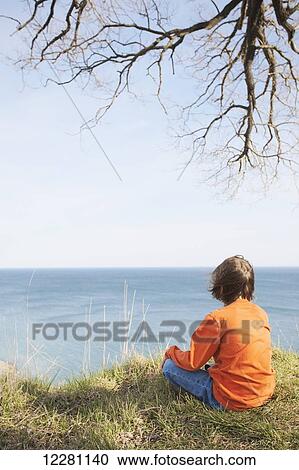 Stock Image - Young boy looking over lake at Scarborough Bluffs; Toronto, Ontario, Canada. Fotosearch