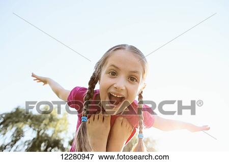 Stock Photo - Young girl balancing on feet pretending to fly; Toronto, Ontario, Canada. Fotosearch