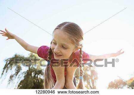 Young girl balancing on feet pretending to fly; Toronto, Ontario, Canada View Large Photo Image Stock Photograph - Young girl balancing on feet pretending to fly; Toronto, Ontario, Canada. Fotosearch