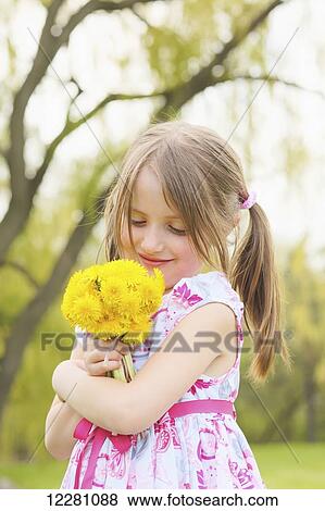 Stock Photo - Young girl holding bunch of dandelion flowers; Toronto, Ontario, Canada. Fotosearch