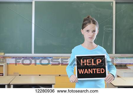 Young girl standing in classroom holding help wanted sign; Toronto, Ontario, Canada View Large Photo Image Stock Photograph - Young girl standing in classroom holding help wanted sign; Toronto, Ontario, Canada. Fotosearch