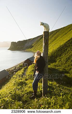 A Girl Watches Her White Kitten Atop A Piling As She Enjoys The Sunset From Her Family's Fish Camp; False Pass, Alaska, United States Of America View Large Photo Image Stock Photograph - A Girl Watches Her White Kitten Atop A Piling As She Enjoys The Sunset From Her Family's Fish Camp; False Pass, Alaska, United States Of America. Fotosearch