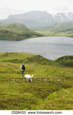 A Woman Hiking With Her Dog And Enjoying The View Of Isanotski Strait In False Pass, From Unimak Island's Eastern Shore; Alaska, United States Of America View Large Photo Image Stock Image - A Woman Hiking With Her Dog And Enjoying The View Of Isanotski Strait In False Pass, From Unimak Island's Eastern Shore; Alaska, United States Of America. Fotosearch