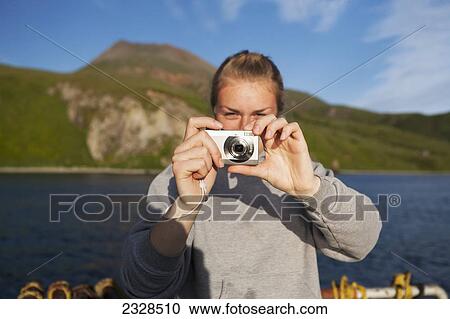 Stock Image - A Woman Taking A Digital Photo While On The Water In False Pass, Also Known As Isanotski Strait; Southwest Alaska, United States Of America. Fotosearch
