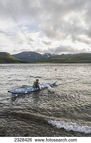 Stock Photograph - A Woman Tending Her Subsistence Salmon Net By Kayak At A Summer Fish Camp On The East End Of Unimak Island On The Edge Of Isanotski Strait; False Pass, Southwest Alaska, United States Of America. Fotosearch
