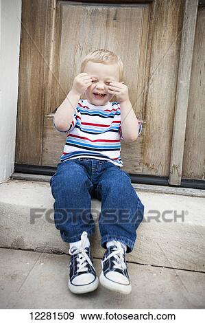 Stock Photo - A young boy sitting on a step and laughing; Nashville, Tennessee, United States of America. Fotosearch