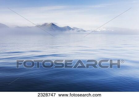 Stock Photo - Blue Ocean Surrounding The Aleutian Islands Leads Into A Fog Bank Partially Concealing The View Of Mountains And Volcanoes; False Pass, Southwest Alaska, United States Of America. Fotosearch
