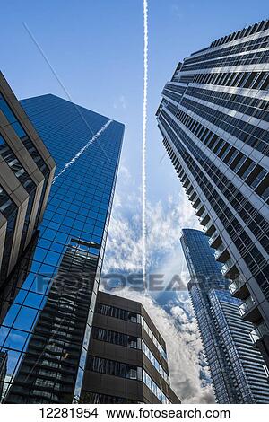 Condensation trail in the blue sky is reflected on surrounding skyscrapers; Toronto, Ontario, Canada View Large Photo Image Picture - Condensation trail in the blue sky is reflected on surrounding skyscrapers; Toronto, Ontario, Canada. Fotosearch