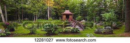 Stock Photo - Country garden with red wooden structure, plants and trees; Knowlton, Quebec, Canada. Fotosearch