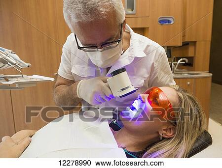 Stock Image - Dentist using fluorescence visualization to check for oral disease; Edmonton, Alberta, Canada. Fotosearch
