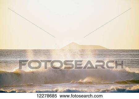 Stock Photography - Golden surf visible from Barking Sands Beach in Kekaha with Lehua visible in the distance; Kekaha, Kauai, Hawaii, United States of America. Fotosearch
