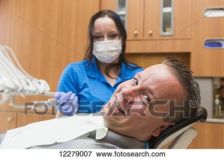Male patient in dental chair during a dental procedure performed by a dental assistant; Edmonton, Alberta, Canada View Large Photo Image Stock Photo - Male patient in dental chair during a dental procedure performed by a dental assistant; Edmonton, Alberta, Canada. Fotosearch