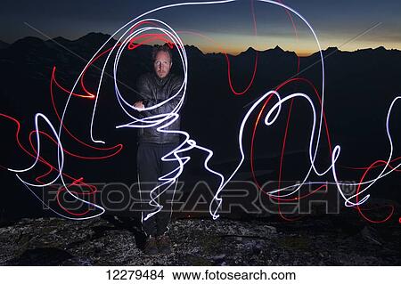 Man on mountain edge at night with light painting; Skagway, Alaska, United States of America View Large Photo Image Picture - Man on mountain edge at night with light painting; Skagway, Alaska, United States of America. Fotosearch