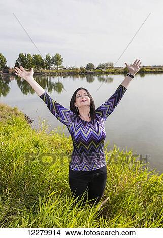 Mature woman raising her hands in worship at a city park in autumn; St. Albert, Alberta, Canada View Large Photo Image Picture - Mature woman raising her hands in worship at a city park in autumn; St. Albert, Alberta, Canada. Fotosearch