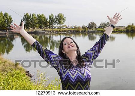Mature woman raising her hands in worship at a city park in autumn; St. Albert, Alberta, Canada View Large Photo Image Stock Image - Mature woman raising her hands in worship at a city park in autumn; St. Albert, Alberta, Canada. Fotosearch