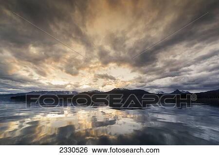 Stock Photograph - Morning Light And Clouds Reflect On The Glassy Waters Of Kachemak Bay, Kenai Peninsula; Alaska, United States Of America. Fotosearch