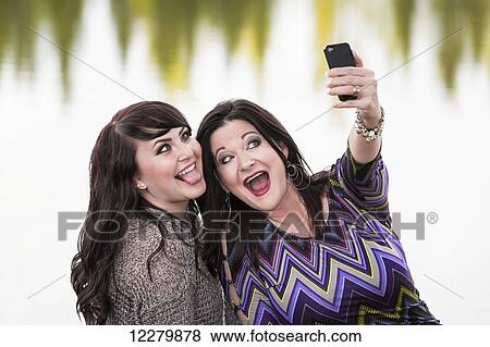 Mother and daughter spending quality time together and taking a selfie outdoors in a city park in autumn; St. Albert, Alberta, Canada View Large Photo Image Stock Photo - Mother and daughter spending quality time together and taking a selfie outdoors in a city park in autumn; St. Albert, Alberta, Canada. Fotosearch