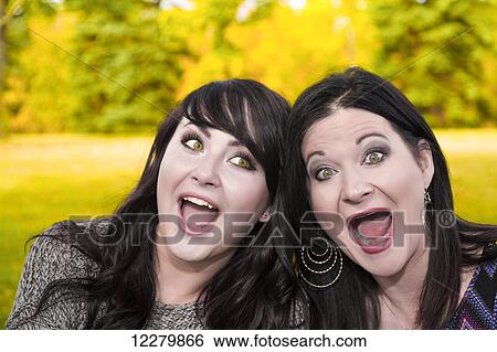 Stock Photograph - Mother and daughter spending quality time together and making a silly pose outdoors in a city park in autumn; St. Albert, Alberta, Canada. Fotosearch