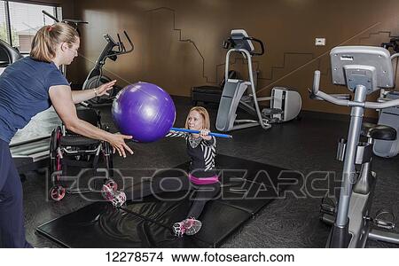 Physiotherapist assisting young woman with spinal cord injury in performing resistance ball toss exercises; Edmonton, Alberta, Canada View Large Photo Image Picture - Physiotherapist assisting young woman with spinal cord injury in performing resistance ball toss exercises; Edmonton, Alberta, Canada. Fotosearch