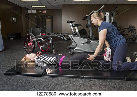 Physiotherapist assisting young woman with spinal cord injury in performing single leg hip flexion exercises; Edmonton, Alberta, Canada View Large Photo Image Stock Image - Physiotherapist assisting young woman with spinal cord injury in performing single leg hip flexion exercises; Edmonton, Alberta, Canada. Fotosearch