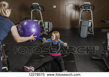 Physiotherapist assisting young woman with spinal cord injury in performing resistance ball toss exercises; Edmonton, Alberta, Canada View Large Photo Image Stock Photography - Physiotherapist assisting young woman with spinal cord injury in performing resistance ball toss exercises; Edmonton, Alberta, Canada. Fotosearch
