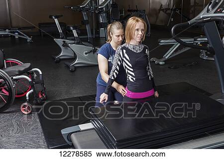 Physiotherapist assisting young woman with spinal cord injury in performing high knee balance with no hands exercises; Edmonton, Alberta, Canada View Large Photo Image Stock Photography - Physiotherapist assisting young woman with spinal cord injury in performing high knee balance with no hands exercises; Edmonton, Alberta, Canada. Fotosearch