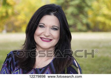 Stock Photo - Portrait of a beautiful mature woman outdoors in a city park in autumn; St. Albert, Alberta, Canada. Fotosearch