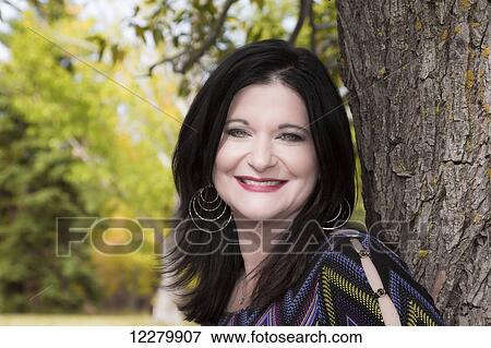 Portrait of a beautiful mature woman outdoors in a city park in autumn; St. Albert, Alberta, Canada View Large Photo Image Stock Photo - Portrait of a beautiful mature woman outdoors in a city park in autumn; St. Albert, Alberta, Canada. Fotosearch